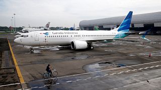 Image: An official rides a bicycle as he passes Garuda Indonesia's Boeing 7
