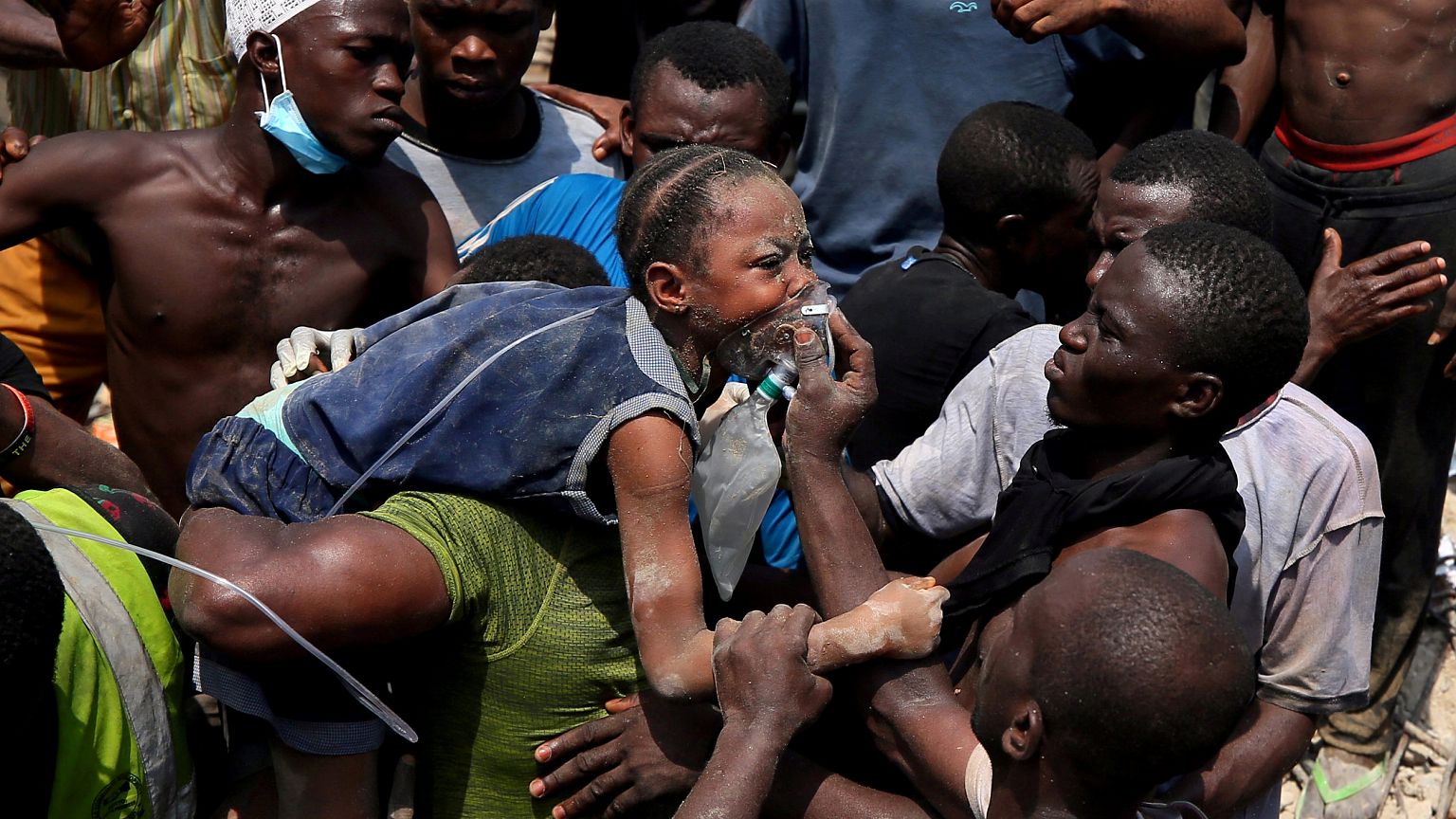 Image: Rescue workers carry a child from the site of a collapsed building i