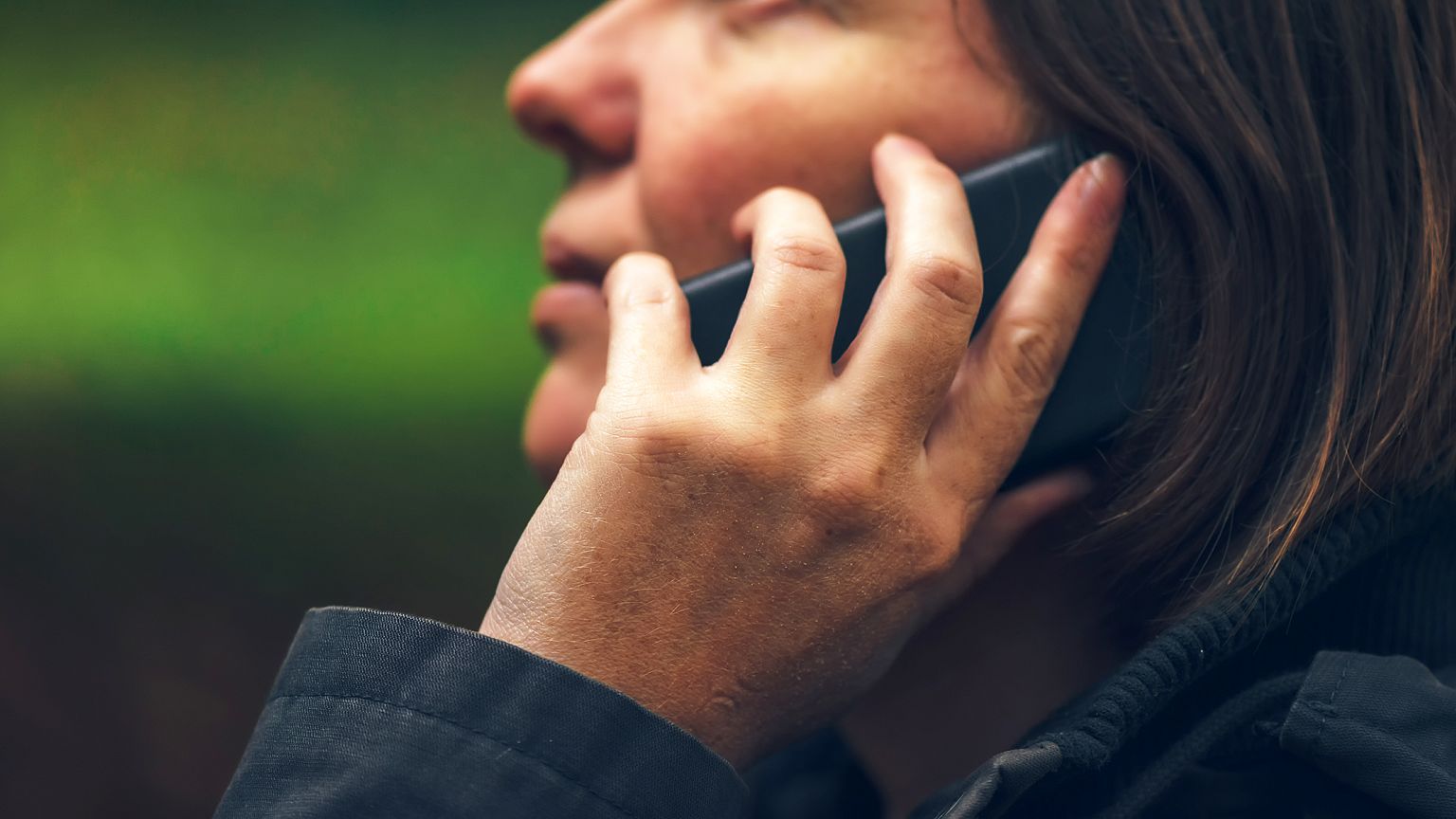 Woman with serious face expression talking on phone in park