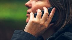 Woman with serious face expression talking on phone in park