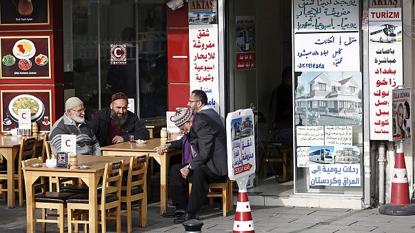 Image: Men chat in front of a real estate agency in Istanbul which has Arab Image: Men chat in front of a real estate agency in Istanbul which has Arab