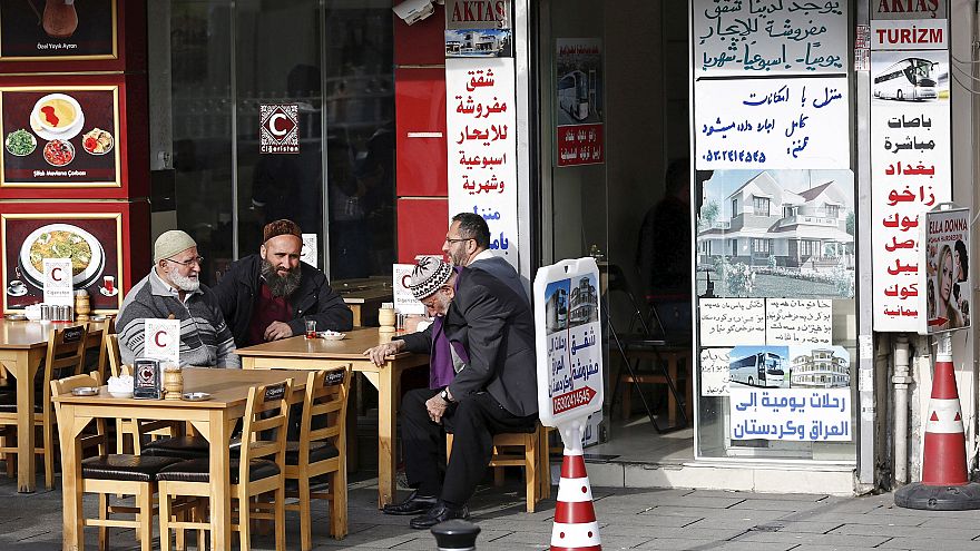 Image: Men chat in front of a real estate agency in Istanbul which has Arab