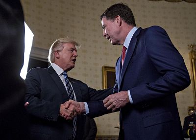 U.S. President Donald Trump, center, shakes hands with James Comey, director of the Federal Bureau of Investigation (FBI), during an Inaugural Law Enforcement Officers and First Responders Reception in the Blue Room of the White House in Washington.