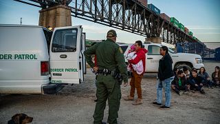 Image: A group of Brazilian migrants board a US Border Patrol van in Sunlan
