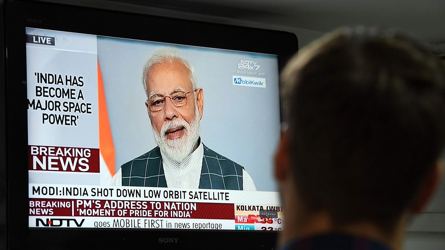Image: A man watches Indian Prime Minister Narendra Modi's address to the n