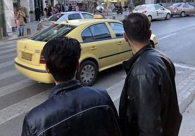 Fazul, left, crosses a street in central Athens alongside Khasim on March 29, 2018.