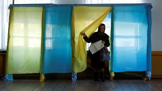 Image: A woman walks out of a voting booth at a polling station during a pr