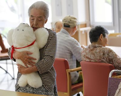 A woman holds a therapeutic robot named Paro at a retirement home in Japan.