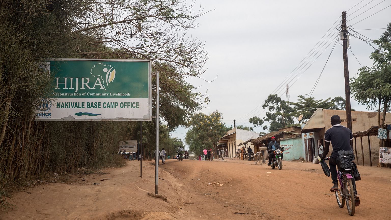 Image: A refugee cycles past a sign pointing to the office of one of UNHCR'