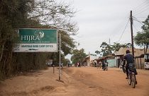 Image: A refugee cycles past a sign pointing to the office of one of UNHCR'
