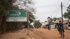 Image: A refugee cycles past a sign pointing to the office of one of UNHCR'