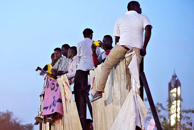 Protesters sit on a torn billboard during a rally demanding Sudanese President Omar Al-Bashir step down on Wednesday.