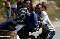 جوانان فلسطینی یک زخمی را از میدان دور می‌کنند
