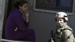 Image: An Israeli soldier walks past a Palestinian girl