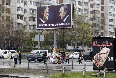 People pass by a billboard depicting Ukraine\'s President Petro Poroshenko and Russian President Vladimir Putin looking at each other in Kiev. Writing on the board reads: "A decisive choice."