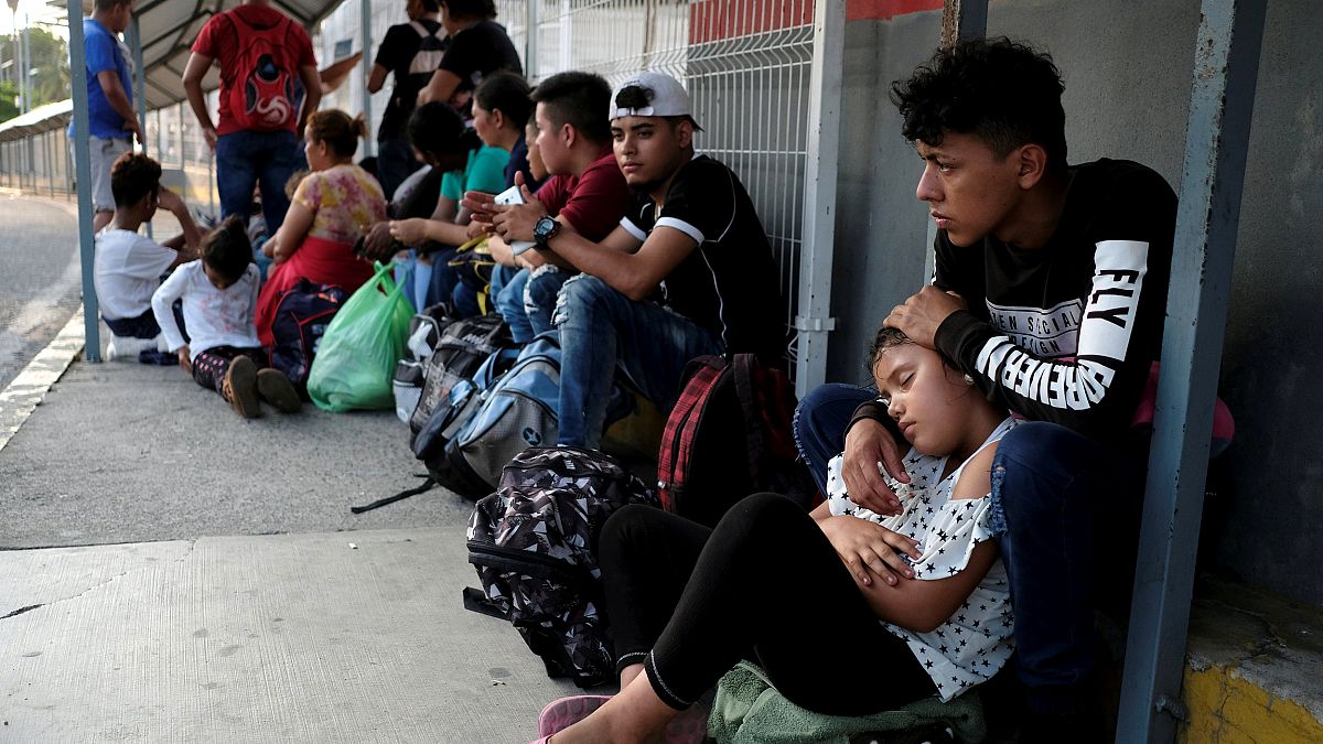 Image: Migrants from Honduras wait on the border bridge between Mexico and 