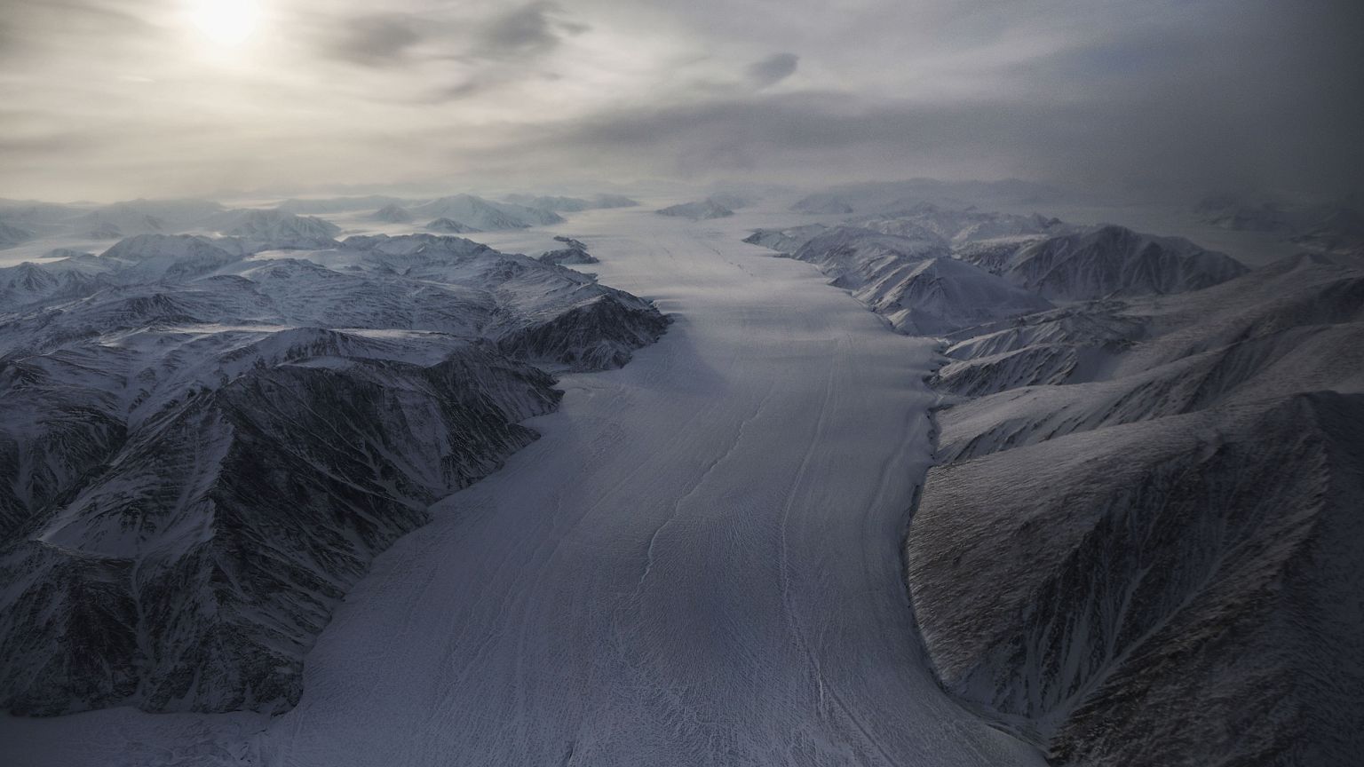 A section of glacier flows between ridges on Ellesmere Island, Canada.