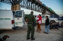 Image: A group of Brazilian migrants board a US Border Patrol van in Sunlan