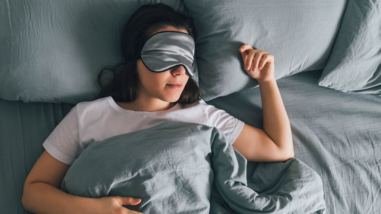 woman sleep in eye patch in grey bed. copy space