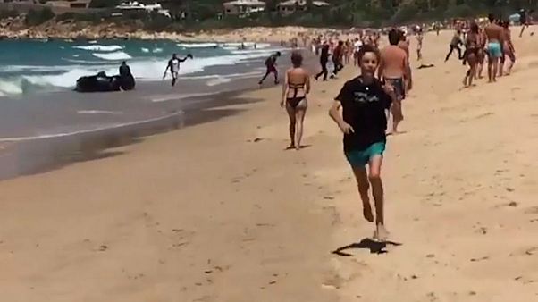 Begegnung am Strand: Flüchtlingsboot trifft auf Touristen Begegnung am Strand: Flüchtlingsboot trifft auf Touristen