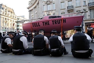 Police officers surround the pink boat which climate change activists used as a central point of their encampment as they occupied the road junction at Oxford Circus in central London on April 19, 2019.