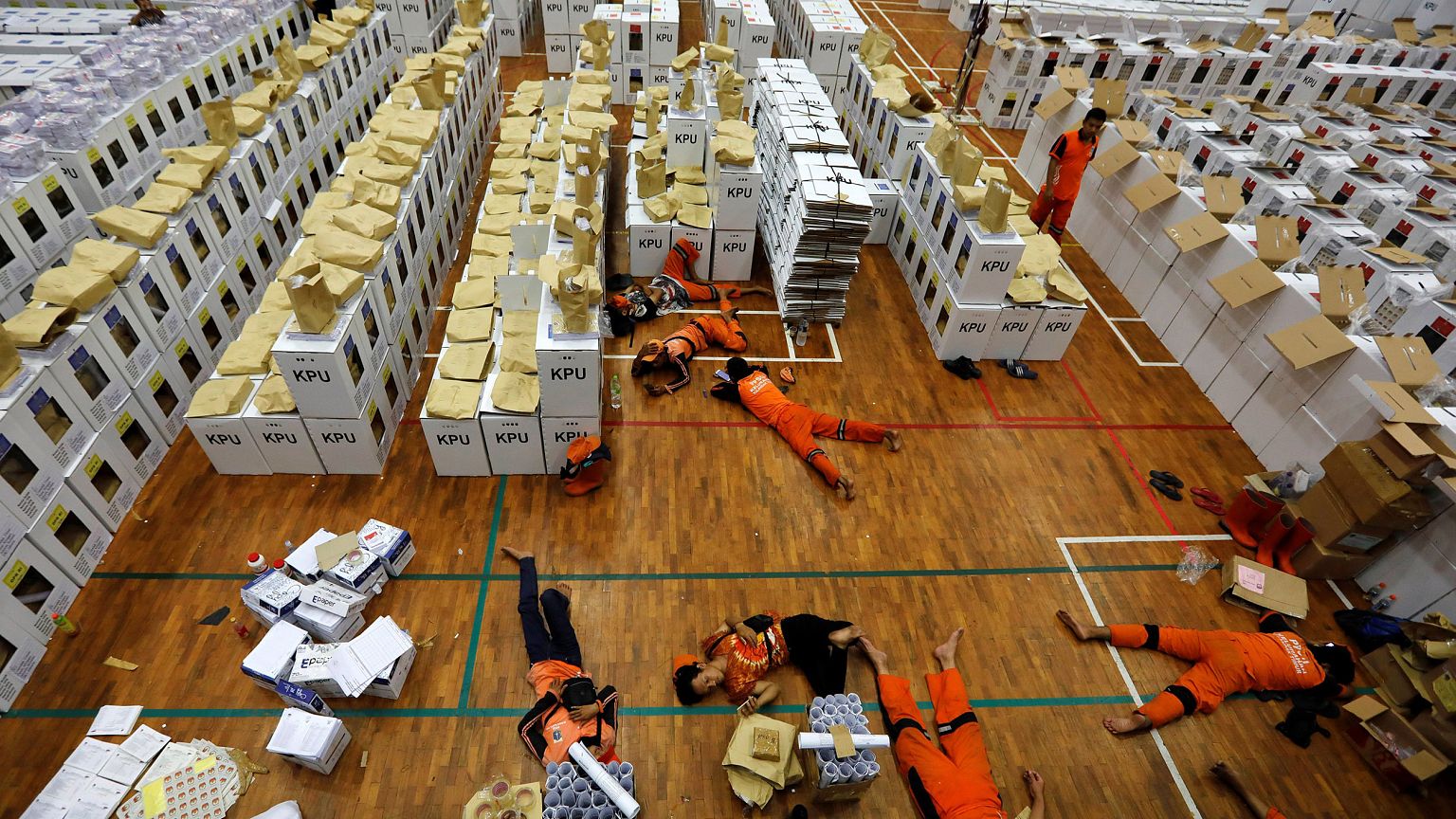 Image: Workers lay during a break as they prepare election materials in a w