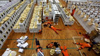 Image: Workers lay during a break as they prepare election materials in a w