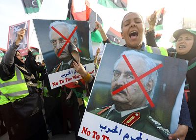 A Libyan woman hits a portrait of Khalifa Haftar with a shoe during a demonstration in Tripoli\'s Martyrs Square on April 19.
