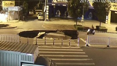 Watch: Phone-watching motorcyclist falls into sinkhole