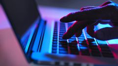 Silhouette of male hand typing on laptop keyboard at night