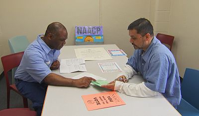 Prisoners Foster Bates, left, and Santanu Basu go over materials they use to register fellow inmates to vote.