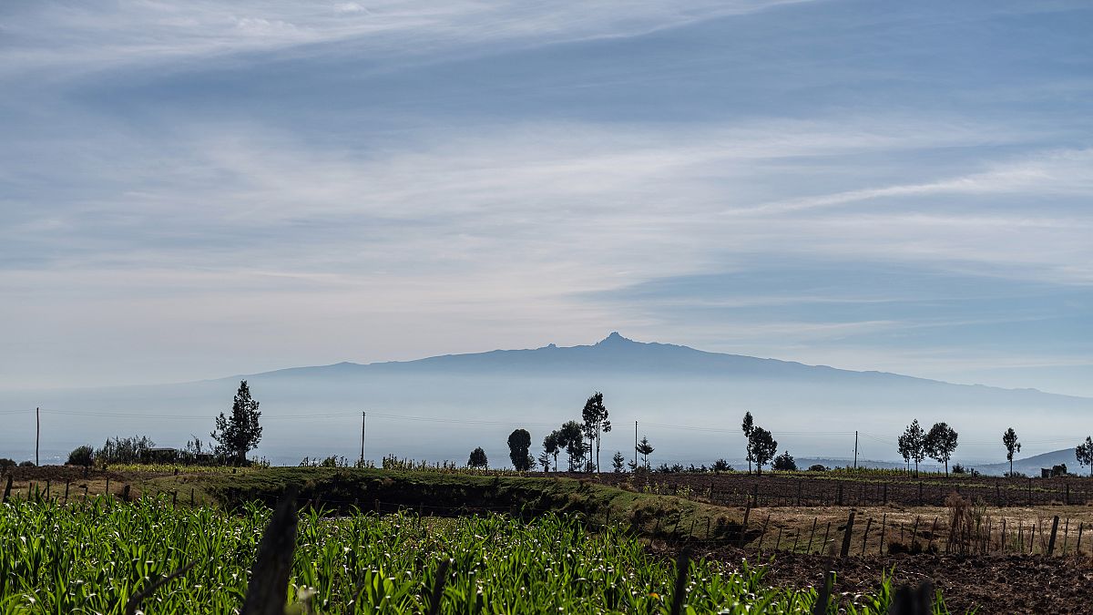 Image: Mt. Kenya peeks out from the clouds beyond a small farm in Embaringo