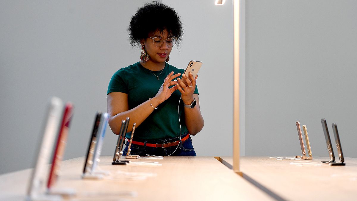 Image: An Apple Store employee uses an iPhone during the grand opening and 