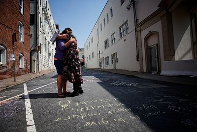 Jenn Franklin, left, and Gretchen Burgess embrace near a makeshift memorial for Heather Heyer, in Charlottesville, Virginia on Aug. 12, 2018 .