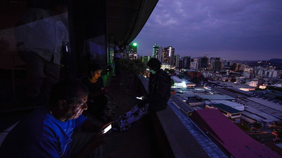 Image: Journalists use their smartphones during a power cut in Caracas, Ven