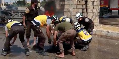 White Helmets members also know as the Syrian Civil Defence putting a body into a bag in a town, said to be Saraqib, Idlib province, Syria on May 22, 2019.
