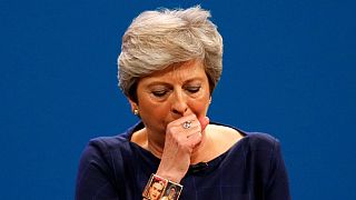 Scenografia che cade, attacco di tosse e intervento comico: bad Day per Theresa May