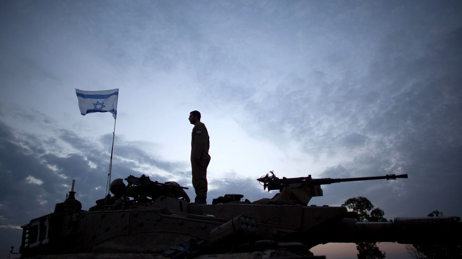 Image:  An Israeli soldier stands on a tank on Israel's border with Gaza St