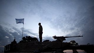 Image:  An Israeli soldier stands on a tank on Israel's border with Gaza St