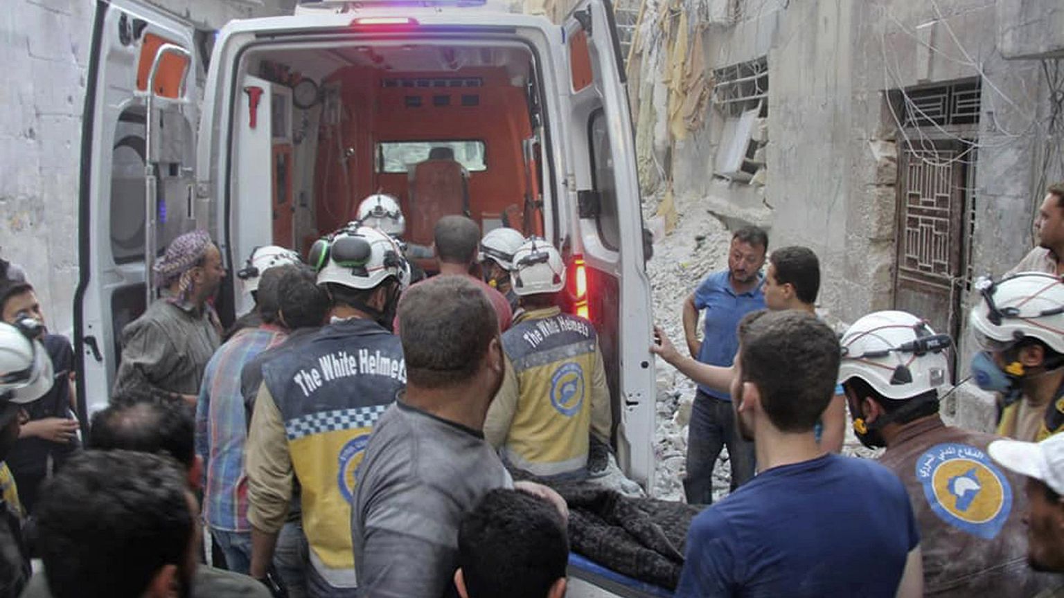 Image: A victim is carried from a destroyed building in Syria's Idlib provi