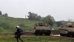 Image: FILE PHOTO: An Israeli soldier walks past armoured Israeli military 