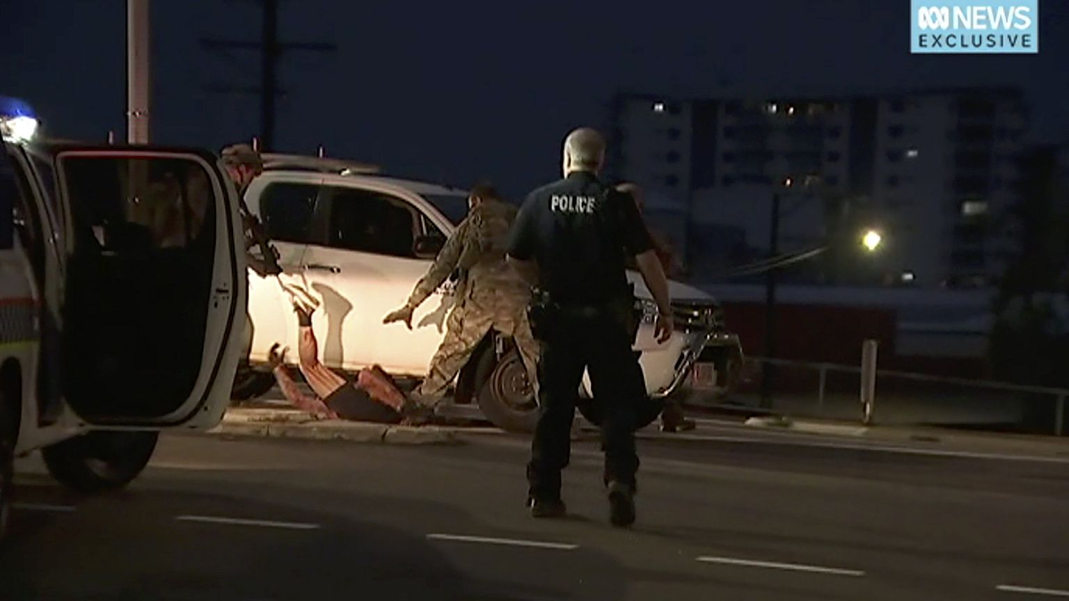 Police apprehend a suspect on the ground next to a white truck, on Tuesday,