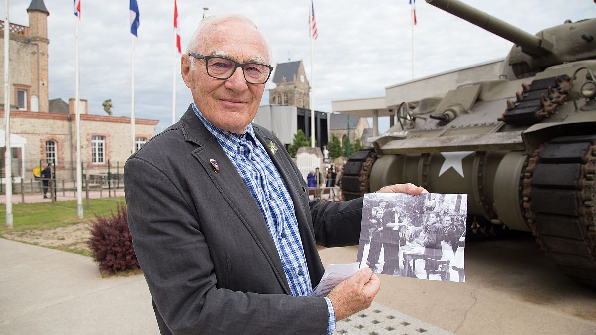 Image: Henry-Jean Renaud holds a photo of himself after the liberation outs