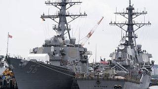 Image: The USS John S. McCain (DDG 56) destroyer, left, is moored in a dock