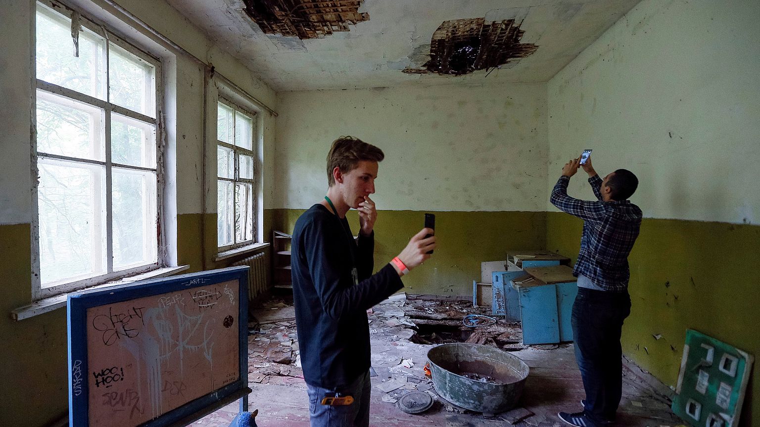 Image: Visitors take pictures at a kindergarten in the abandoned village of