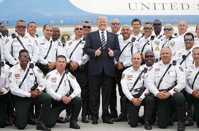 President Donald Trump gives the thumbs-up as he poses with local law enforcement officers before boarding Air Force One at Palm Beach International Airport in Florida on April 22, 2018.
