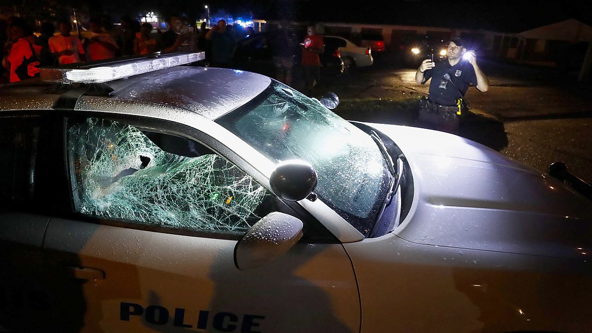 Image: A Memphis police officer looks over a damaged squad car after protes