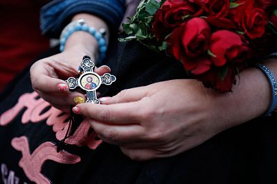 A woman holds a cross and roses as the first mass is held at the Notre-Dame in Paris on June 15, 2019.