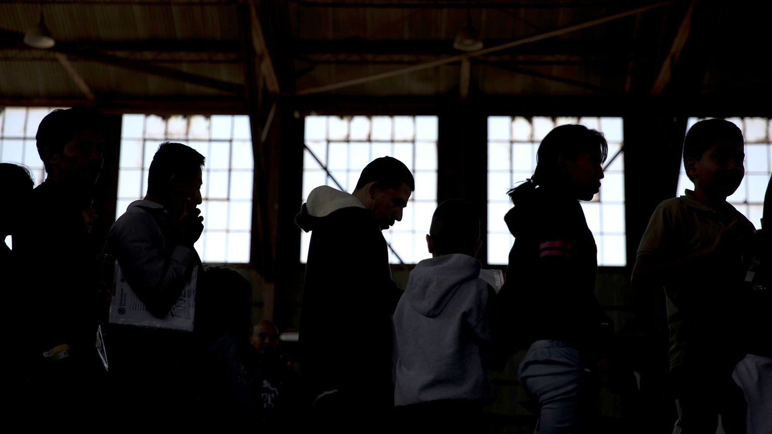 Image: Migrants wait to be transported from the intake processing area to t