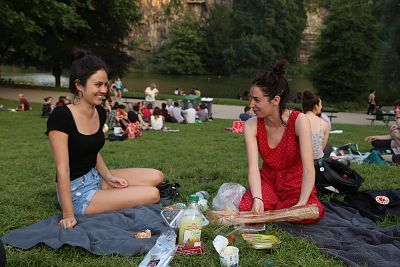 Alice Rustique, 26, left, and Elora Fernandez, 26, make the most of the heat wave hitting Europe by enjoying an evening picnic in Parc des Buttes-Chaumont in Paris.